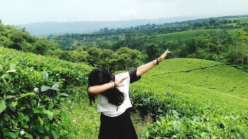 Woman gesturing while standing on landscape