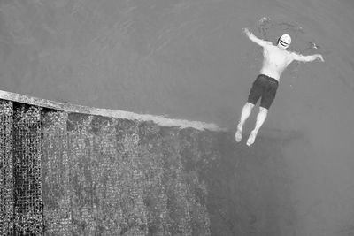 Full length rear view of shirtless man swimming in lake