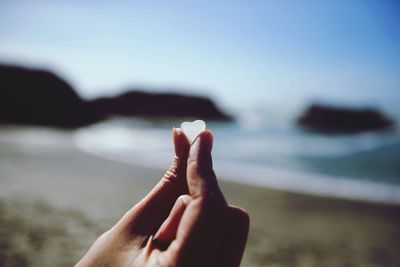 Close-up of woman hand against sea