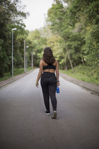 Rear view of woman with umbrella on road