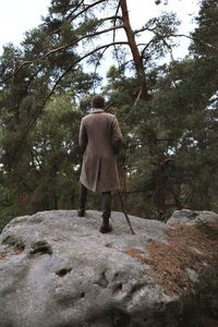 Rear view of man walking on rock in forest