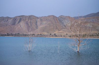 Scenic view of lake and mountains against clear blue sky