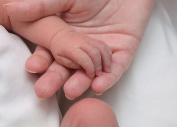 Close-up of woman holding baby hand at home