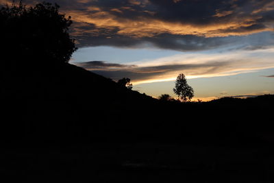 Silhouette trees on landscape against sky during sunset