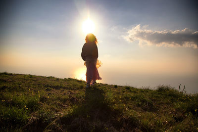 Man standing on field against sky during sunset