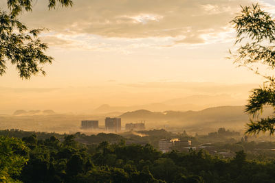 Scenic view of trees and buildings against sky during sunset