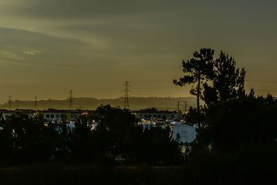 Silhouette trees and buildings against sky at sunset