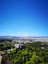High angle view of trees and buildings against blue sky