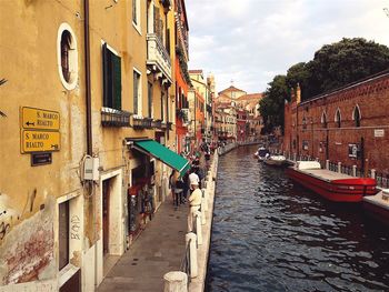 Canal amidst buildings in city against sky