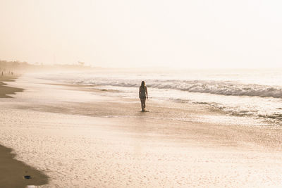 Rear view of woman at beach against sky