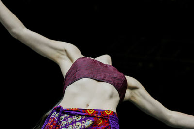 Midsection of woman standing against black background