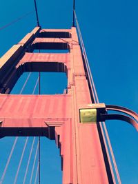 Low angle view of suspension bridge against blue sky