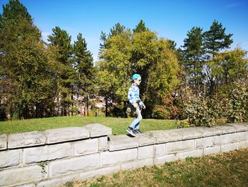 Boy walking on wall against trees