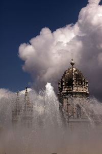 View of mosteiro dos jeronimos in fountain against cloudy sky