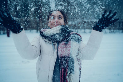 Rear view of woman with arms raised standing on snow