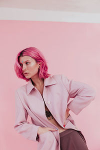 Beautiful young woman standing against colored background