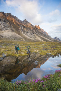 Reflection of backpackers hiking through akshayak pass, canada.