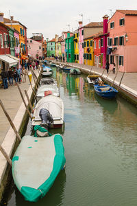 Boats moored in canal amidst buildings in city