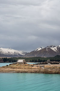 Scenic view of lake tekapo in morning with new zealand southern alps mountains against gloomy sky.