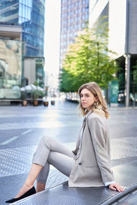Young woman sitting on street in city