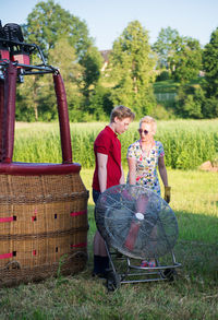 Mother and son with electric fan standing on field