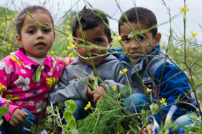 Portrait of siblings and plants on land