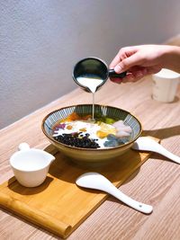 Hand holding glass of bowl on table