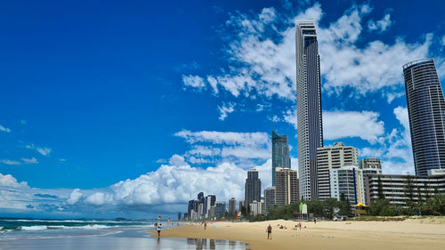 Panoramic view of beach and buildings against blue sky