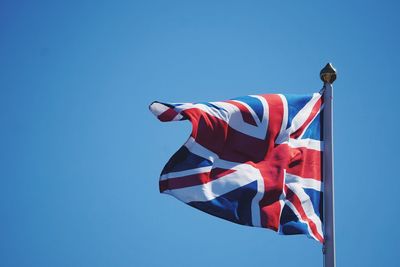 Low angle view of british flag against waving against clear blue sky