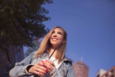 Smiling woman in city against clear blue sky