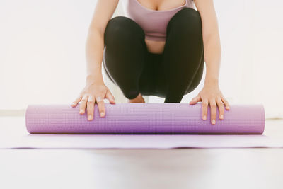 Crop image of woman hands rolling yoga mat, preparing for doing yoga. working out at home.