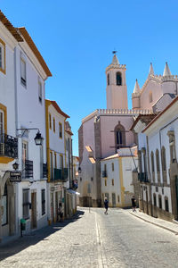 Street amidst buildings in city against clear blue sky