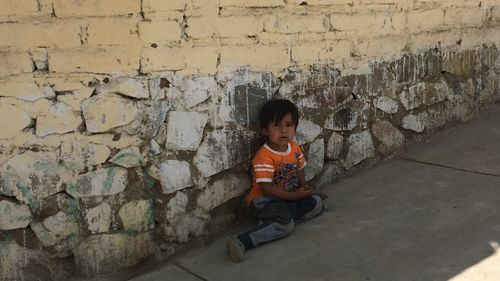 Full length of boy sitting on wall