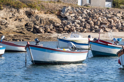 Boats moored on rock by sea