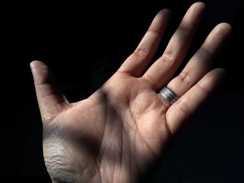 Cropped hand of woman wearing ring against black background