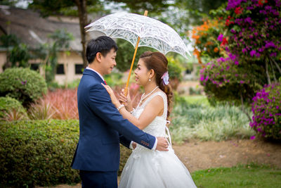 Side view of bride and bridegroom standing at park