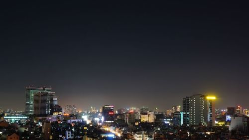 Illuminated cityscape against clear sky at night