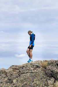 Full length of woman standing on rock against sky