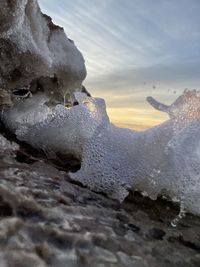 Close-up of frozen rocks against sky during winter