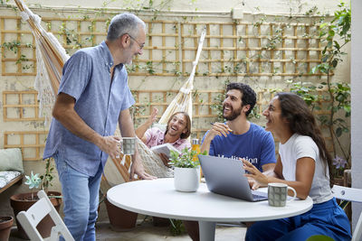 Side view of friends using laptop at table