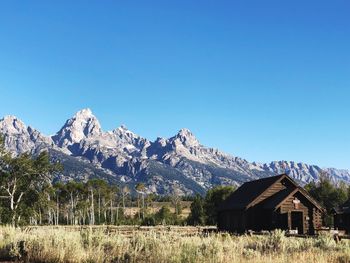 Scenic view of house and mountains against clear blue sky