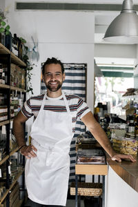 Portrait of smiling male entrepreneur with hand on hip in bakery