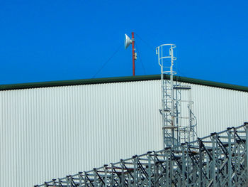 Low angle view of industry against clear blue sky