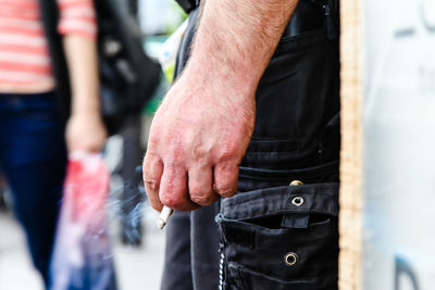 Midsection of man holding cigarette