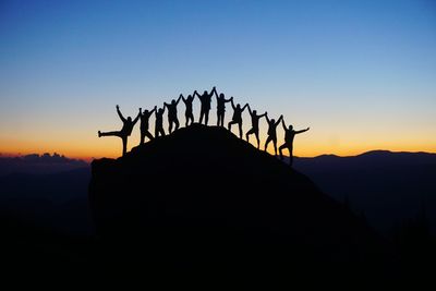 Silhouette birds on mountain against clear sky during sunset