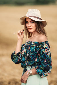 Portrait of beautiful young woman wearing hat standing outdoors