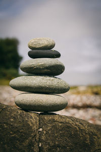 Close-up of stone stack on rock against sky