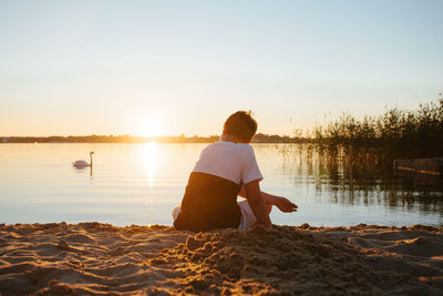 Lake jamno, poland - boy and his dog on lake at sunset