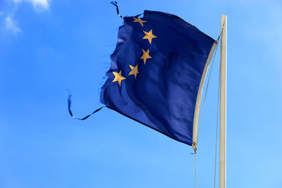 Low angle view of torn european union flag against sky