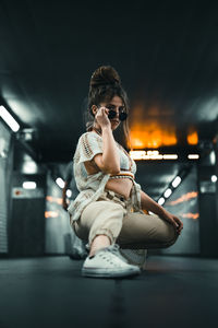 Full length of woman sitting at illuminated nightclub